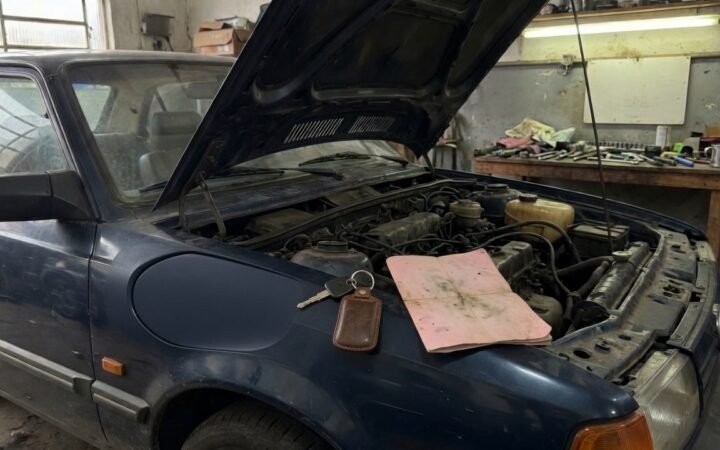 Carro usado com o capo aberto em oficina, chave e laudo de vistoria sobre o paralama, ilustrando vicio oculto em veiculo